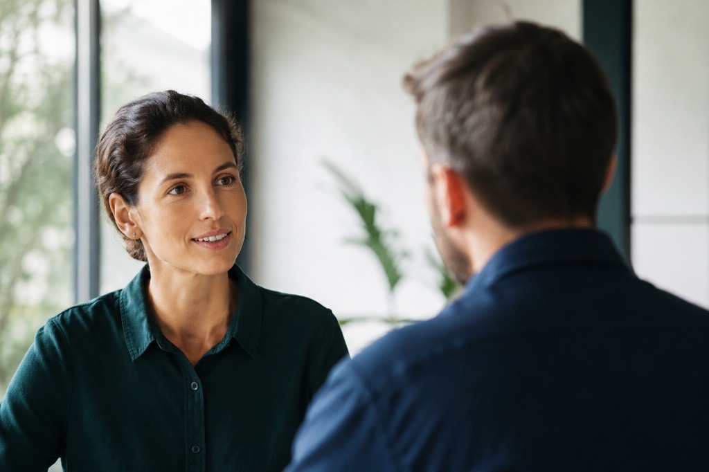 Two professionals in a bright office having a calm, collaborative conversation about a business matter