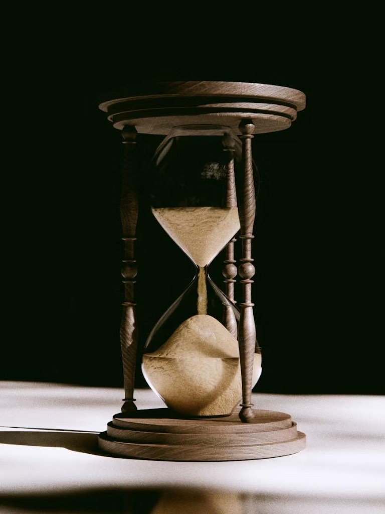 Wooden hourglass with sand flowing, symbolizing payment deadlines and time running out