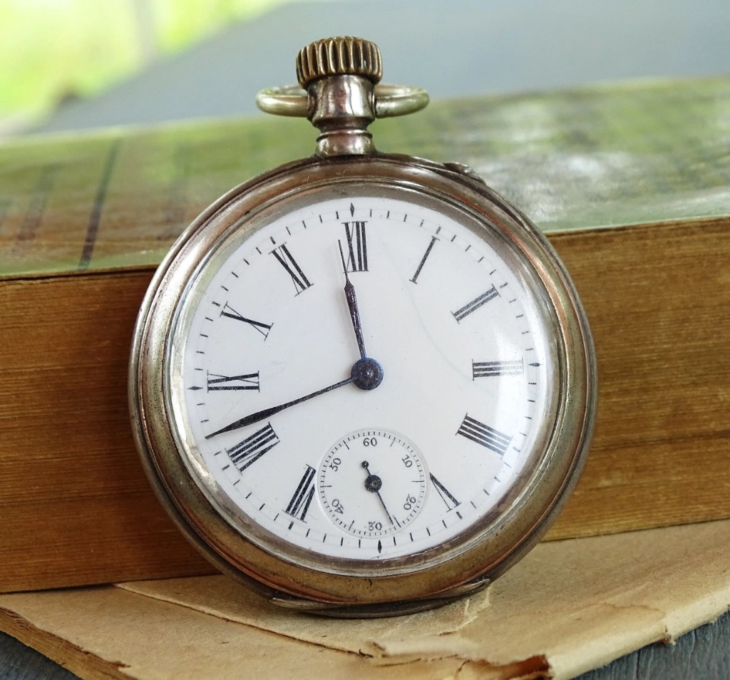 Antique pocket watch on an old book, symbolizing payment deadlines and time